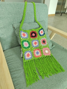 Detail of green crochet tote bag with colorful granny square floral patterns and long tassels