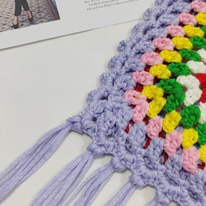 Close-up of colorful handmade crochet knit bag with purple fringe tassels