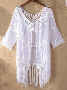Detail of white crochet beach cover-up featuring hollow-out floral knit and long fringe tassels