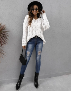 Detail of white cable knit texture on women's V-neck thick sweater with long sleeves