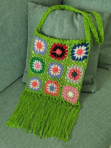 Detail of bohemian crochet flower pattern and long green fringe on a handmade bag