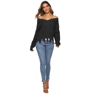 Detail of frayed hem and distressed ripped texture on black V-neck knit sweater