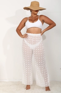 Detalle de los pantalones de playa de malla blanca transparente con pompones y lunares 3D