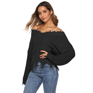 Close-up of black distressed knit sweater with V-neck and ripped detailing on the hem