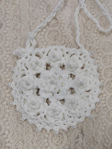 Detail of hand-crocheted white round crossbody bag with 3D floral pattern and pearls