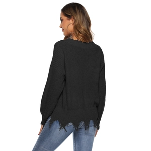 Macro shot of the distressed hem and thick knit texture on a black women's loose sweater
