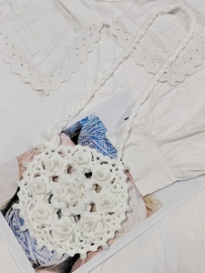 Close-up of white crochet crossbody bag with floral knit texture and pearl beads detail