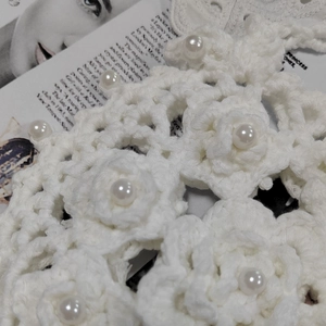 Close-up of white crochet strap with floral patterns and inlaid pearls for a handbag