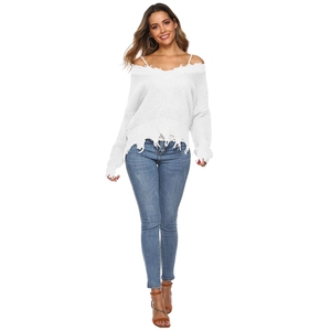 Close-up of white V-neck knit sweater with tassel hem and distressed ripped details