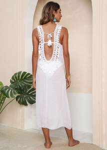Detail of white crochet macramé backless beach dress featuring long fringes and boho pattern