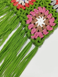 Macro detail of hand-crocheted grandmother square pattern with green fringe tassels