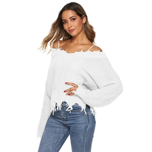Detailed close-up of white off-shoulder knit sweater featuring distressed holes and long fringe
