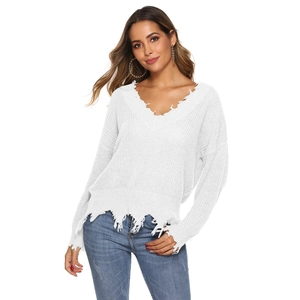 Detail of white V-neck sweater showing raw edge fringe and knitted texture details