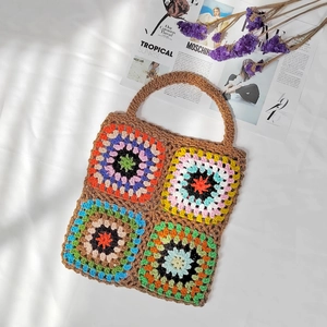 Detailed top view of a handmade granny square crochet tote bag on a white textured fabric