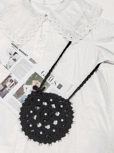 Detailed macro view of black handmade crochet crossbody bag with elegant white pearl accents