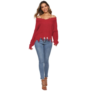 Detail of red off-shoulder knitted sweater with fringe edges and distressed hem design