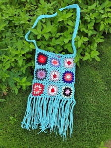 Detailed close-up of handmade crochet tassel bag with colorful granny square patterns