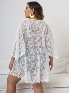 Detail of white floral lace cardigan with pom-pom trim and sheer oversized beach cover-up