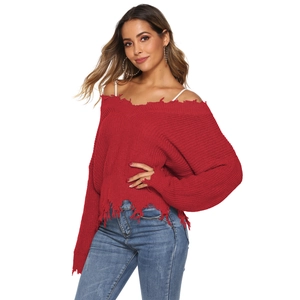 Detailed close-up of red off-shoulder knit sweater with distressed ripped edges