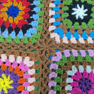 Macro detail of handmade colorful granny square crochet patterns on the women's handbag
