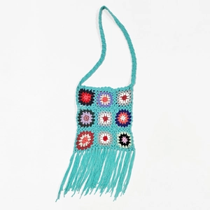 Close-up of handmade crochet crossbody bag with sunflower patterns and long fringe details