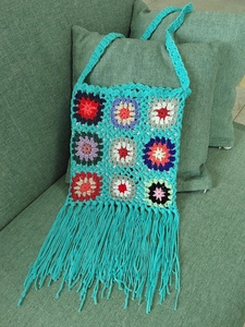 Close-up of handmade crochet crossbody bag featuring colorful floral granny square patterns