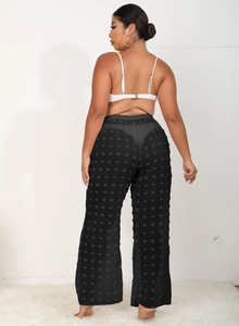 Detalle de pantalones de playa negros transparentes con texturas de pompones de gasa