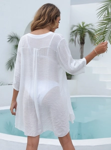 Vue détaillée du dos d'une tunique de plage blanche semi-transparente avec pli creux
