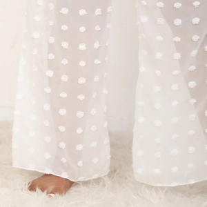 Detalle de pantalón playero blanco de pierna ancha en gasa transparente con lunares en 3D