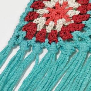 Close-up of handmade crochet flower pattern in red and blue with delicate tassels