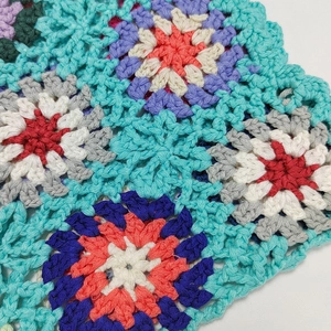 Close-up detail of multi-color granny square crochet pattern with hand-woven floral texture