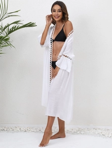 Detail of white beach cover-up with lace edges and ruffled sleeves on a model