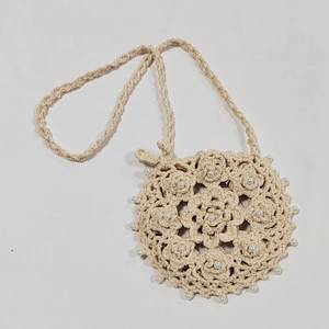 Close-up of handmade crochet round crossbody bag with floral patterns and pearl beads