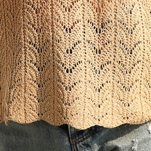 Détail macro du haut en maille crochet kaki avec motif ajouré et texture denim