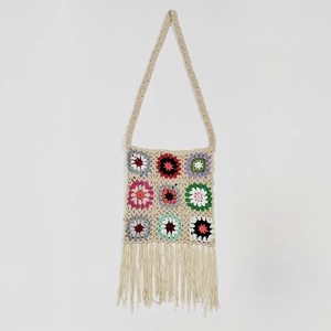 Macro detail of hand-crocheted grandmother square patterns and boho fringe textures