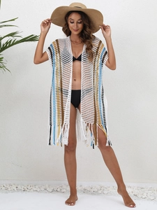 Close-up of bohemian white crochet beach cover-up featuring colorful stripes and fringe