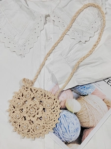 Detailed close-up of beige hand-crocheted round crossbody bag with white pearl decorations