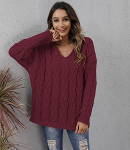 Detail of burgundy V-neck cable knit texture and relaxed shoulder design on sweater