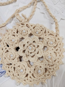 Detail of hand-crocheted beige bag showing floral 3D patterns and white pearl embellishments