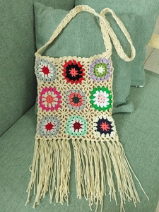 Close-up of bohemian crochet bag with colorful granny squares and elegant beige fringe