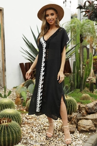 Detail of V-neck beach dress with black lace trim and white crochet fringe decoration
