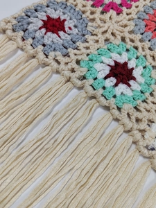 Detail of colorful crochet granny squares and white fringe on a boho tote bag