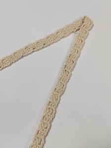 Detail shot of beige crochet bag strap showing intricate knit pattern and texture