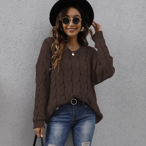 Detail of chunky cable knit texture and V-neck on a loose dark brown sweater