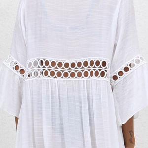 Detailed view of white lace patchwork and textured fabric on beach cover-up sleeves