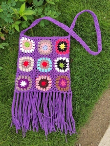 Detailed macro view of colorful crochet granny squares and fringe on the purple bag