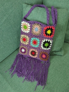 Detail of a purple boho shoulder bag with granny square crochet patterns and long tassels