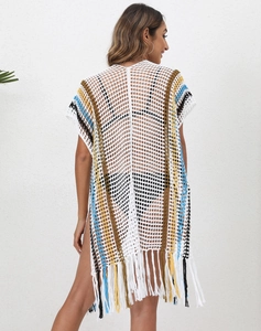 Detail view of colorful crochet patterns and long fringe hem on white beach cover-up
