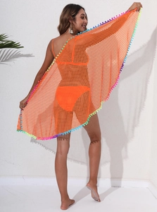 Détail du paréo de plage en résille orange orné de pompons multicolores sur les bords
