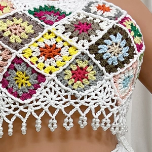 Detail of colorful handmade crochet granny square vest with fringe and pearl beads